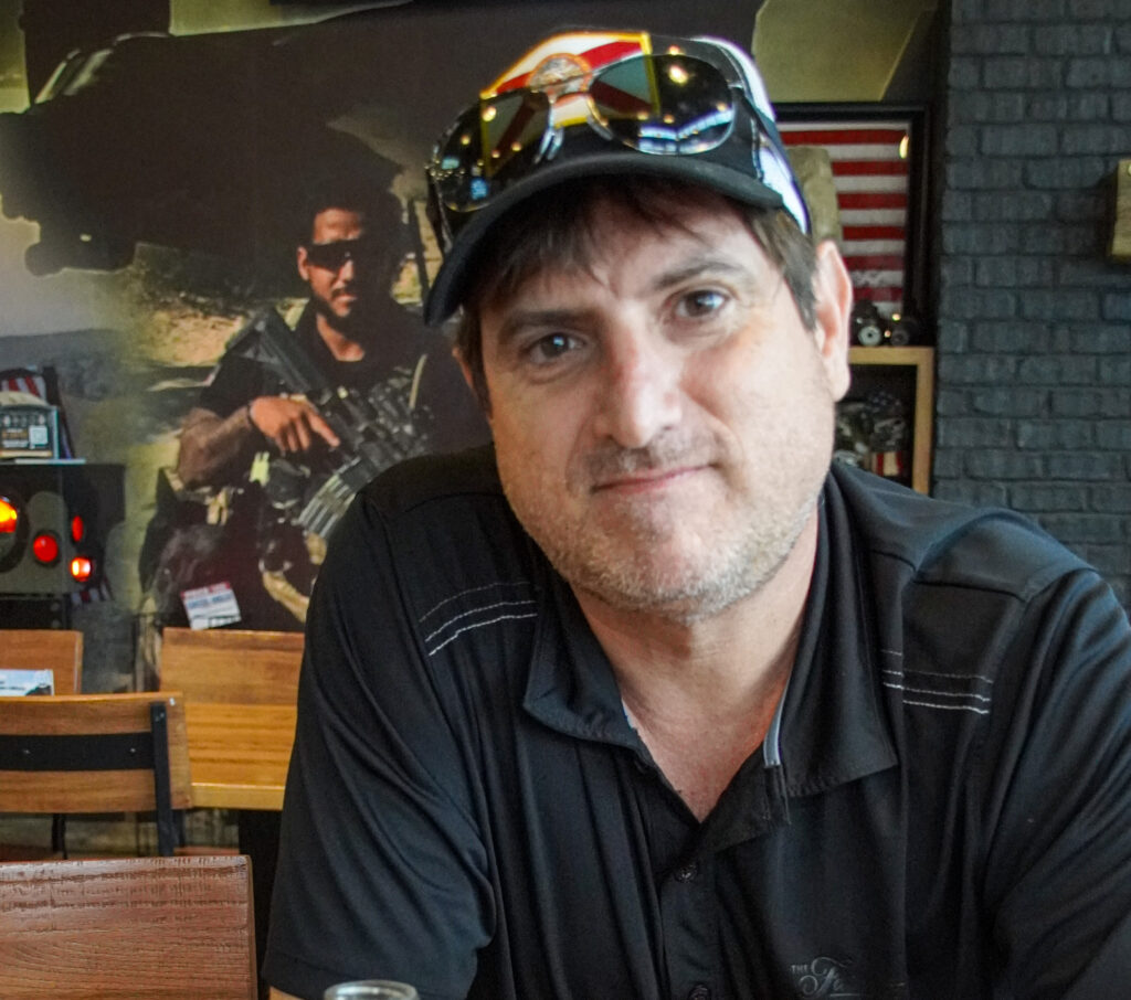 Man looks at a camera in a coffee shop.