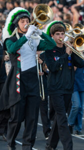 A member of the Choctawhatchee high school style marchers moves forward with trombone in hand and headdress on head to the cheers of Indian fans.