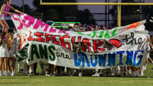 Niceville high school football players run through the sign and smile as they head to their bench before the game.