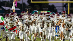 Niceville high school football players run through the sign and smile as they head to their bench before the game.