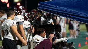 Niceville Eagles football players gather around the screen to watch video of their play on the previous drive.