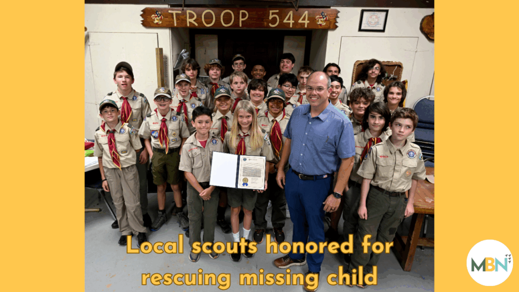 Group of Boy Scouts from Troop 544 standing with Okaloosa County Commissioner Paul Mixon, holding a framed proclamation honoring their role in finding a missing child.