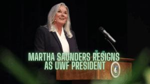 University of West Florida President Martha Saunders speaks at a podium during a public address, smiling as she delivers remarks.