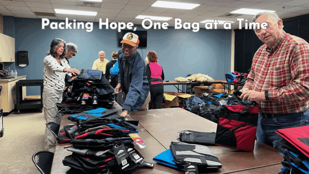 Volunteers from the Kiwanis Foundation of Niceville-Valparaiso pack duffel bags filled with supplies for foster children in a community room.