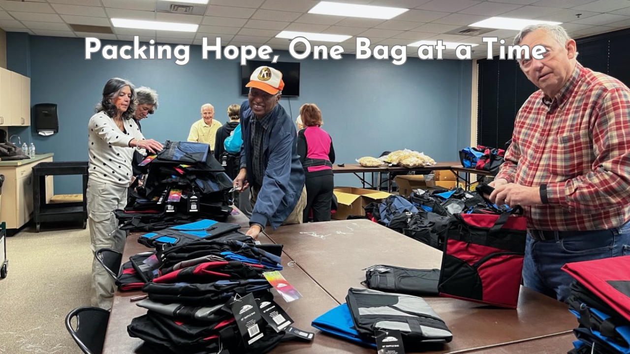 Volunteers from the Kiwanis Foundation of Niceville-Valparaiso pack duffel bags filled with supplies for foster children in a community room.