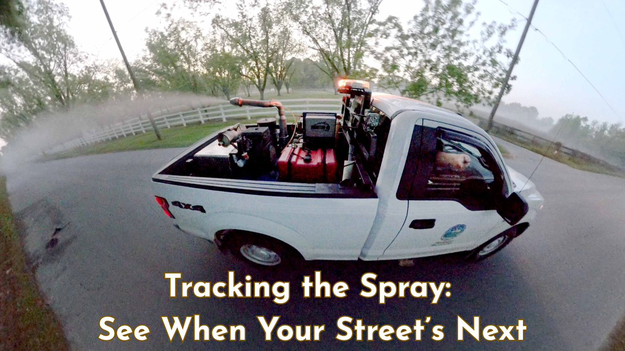 Mosquito control truck spraying mist along a residential road in Okaloosa County at dusk.