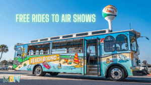 Colorful Pensacola Beach trolley labeled “Beach Bound” parked under a blue sky near the iconic Pensacola Beach water tower.