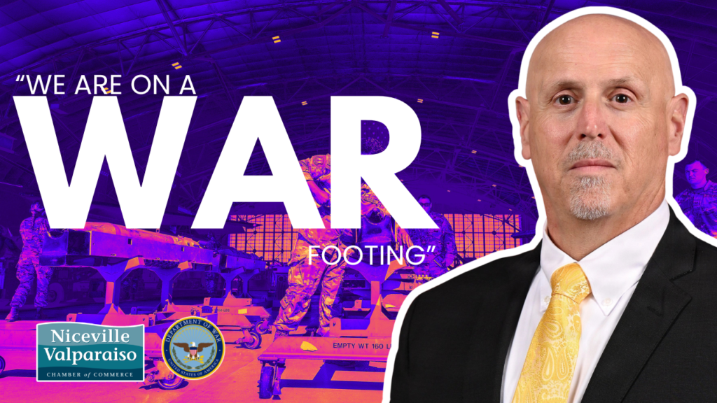 Banner promoting readiness with the text 'WE ARE ON A WAR FOOTING', a man in a suit on the right, and logos for Niceville Valparaiso Chamber of Commerce and the U.S. Department of Defense in the corner.