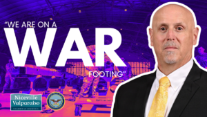 Banner promoting readiness with the text 'WE ARE ON A WAR FOOTING', a man in a suit on the right, and logos for Niceville Valparaiso Chamber of Commerce and the U.S. Department of Defense in the corner.
