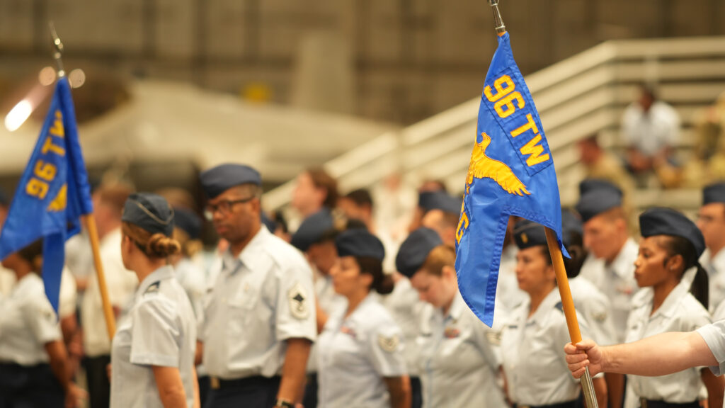 96 testing airmen stand with their guidons as they prepare for the change of command ceremony in the McKinley climatic laboratory on Eglin Air Force Base.