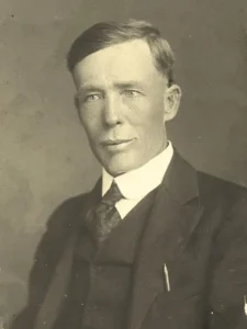 a photo of a man from the early 20th century in a suit and tie.