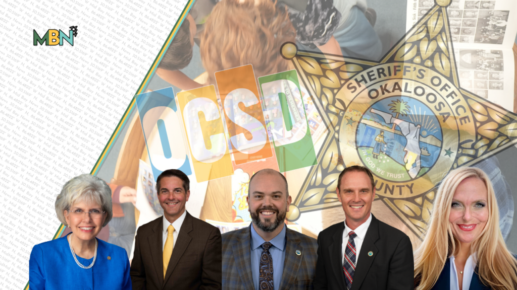 Group of five officials posing in front of an OCSD backdrop with the Okaloosa County Sheriff’s badge logo and colorful OCSD letters behind them, indicating a sheriff’s office event.