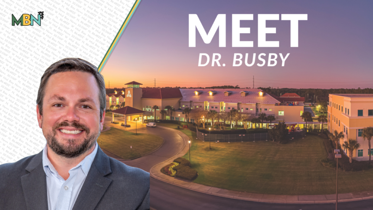 Smiling man in a suit on the left with a campus building at sunset and the title 'MEET DR. BUSBY' on the right, plus the MBN logo in the corner.