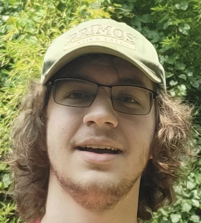a man with shoulder length hair, glasses and a thin beard.